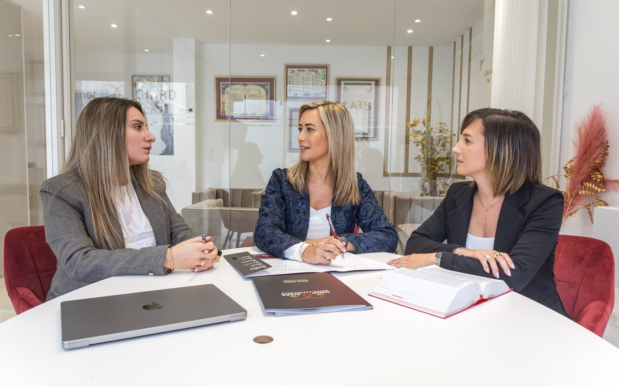 L’équipe du cabinet réunie autour de la table de la salle de réunion, fauteuils velours bordeaux
