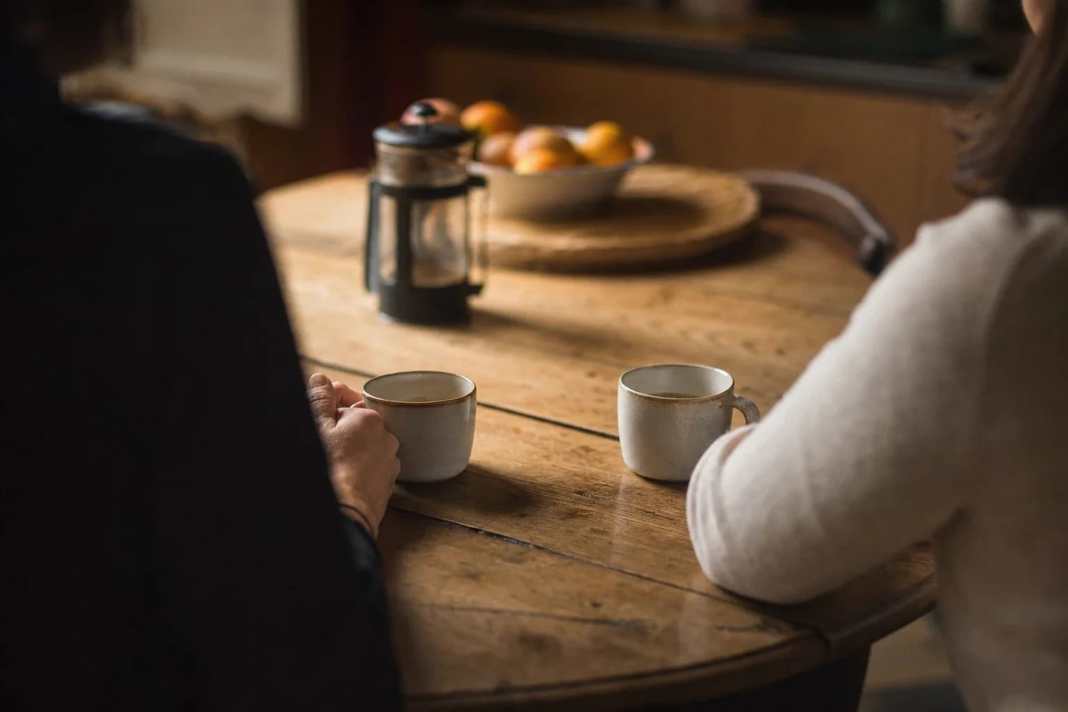 Deux personnes attablées face à face, une tasse de café devant chacune