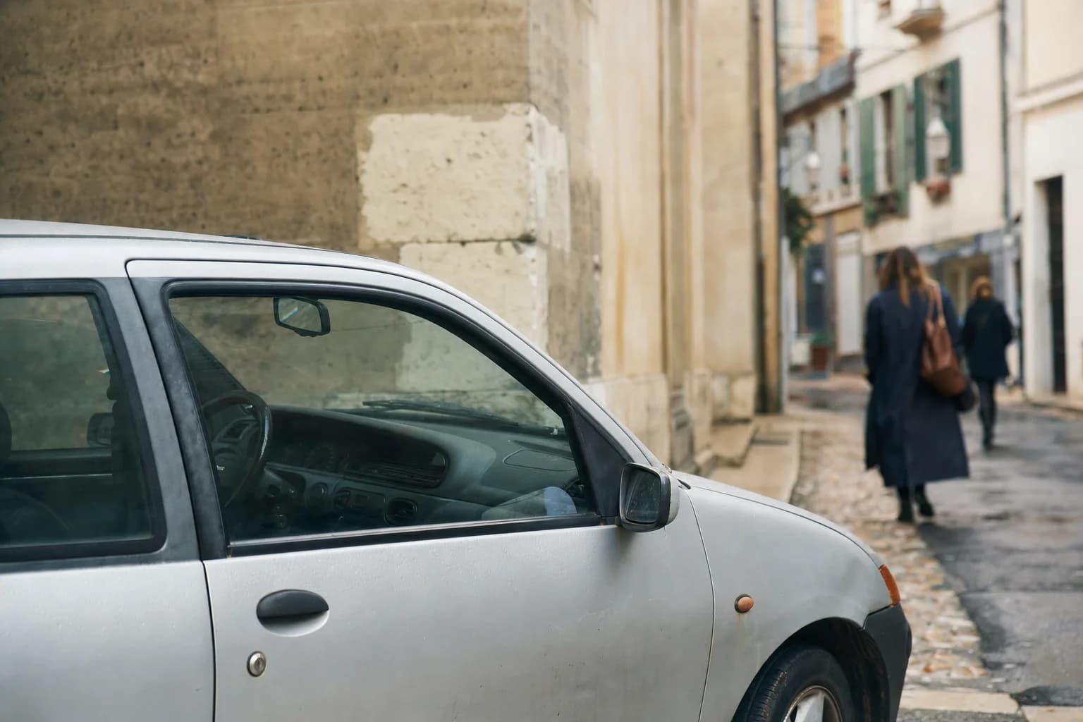Une petite voiture garée dans une rue calme, le siège du conducteur vide