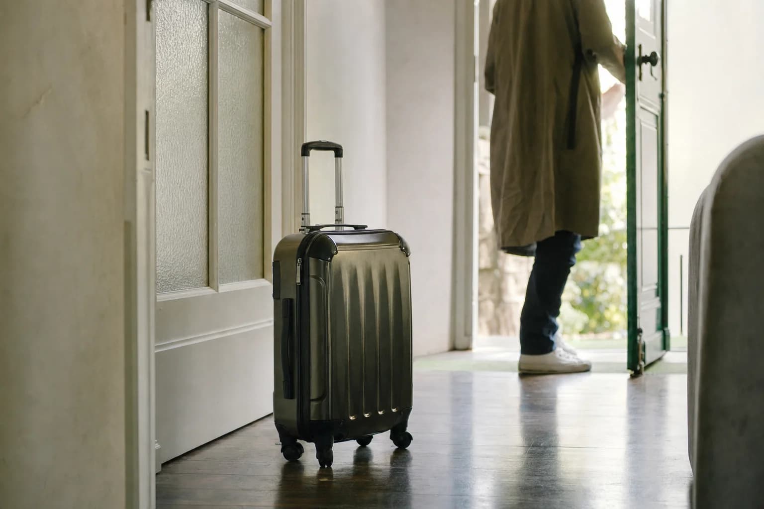 Une valise posée dans l’entrée, près de la porte ouverte
