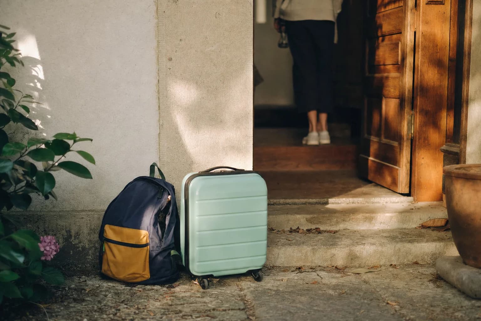 Un sac à dos d’enfant et une petite valise devant la porte d’une maison